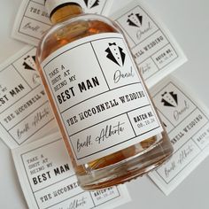 a bottle of alcohol sitting on top of some paper tags with labels around it that say best man