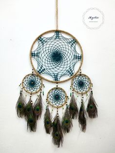 a blue dream catcher with feathers hanging from it's side on a white wall