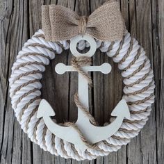 a white anchor with a bow hanging on a wooden door hanger that has rope and jute around it