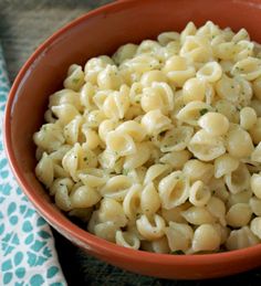 a bowl filled with macaroni and cheese on top of a table next to a spoon