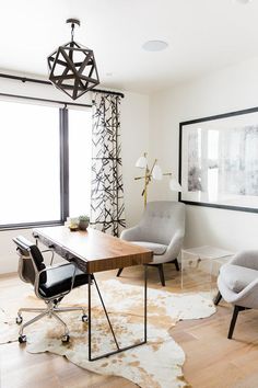 an office with two chairs and a desk in front of a large window on the wall