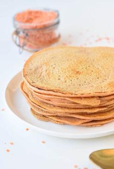 a stack of pancakes sitting on top of a white plate next to a measuring spoon