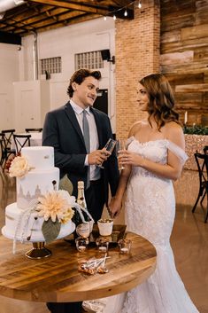 a bride and groom standing in front of a table with a wedding cake on it