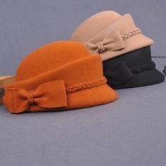 three hats with bows are sitting on a table next to a pair of wooden scissors