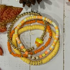 three yellow and orange bracelets hanging from a hook on a white wall next to a pine cone