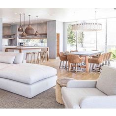 a living room filled with furniture next to a kitchen and dining room table in front of a large window