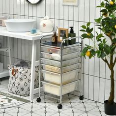 a white sink sitting next to a tree in a bathroom on top of a tiled floor