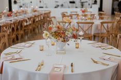 the table is set with flowers, candles and place settings for guests to sit at