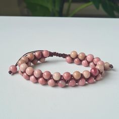 This glamorous bracelet is beautifully handcrafted with 6mm rhodonite healing stone beads. The wrap is made from high-quality macrame cord and measures 6.7 inches (17cm), adjustable to fit your wrist perfectly. 🌸 Rhodonite is a stone of compassion, an emotional balancer that clears away emotional wounds and scars from the past, and that nurtures love. It stimulates, clears and activates the heart. Rhodonite grounds energy, balances yin-yang, and aids in achieving one's highest potential. It hea Braided Macrame, Gift Tissue Paper, Handcrafted Bracelets, Natural Stone Bracelets, Macrame Bracelet, Bracelet Boho, Macrame Cord, Gifts For Your Mom, Macrame Bracelets