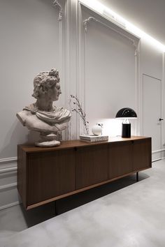 a busturine is sitting on top of a wooden cabinet in the middle of a room