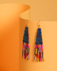 Lightweight, colorful, and unique these handwoven Japanese glass beaded earrings combine tubular beads with classic smaller beads for contrast. The hand strung fringe is made up of beautiful bead colors including gold for a touch of shimmer, which are organized in abstract lines. The beaded portion of the earring is hung from a hypoallergenic 14K gold plated ear wire. These earrings are designed by myself and made in conjunction with my team of women artisans from vulnerable communities in Medel Multicolor Dangle Beaded Earrings With Gold Beads, Multicolor Heishi Beads Jewelry With Dangling Beads, Multicolor Beaded Fringe Earrings For Party, Colorful Heishi Bead Dangle Earrings, Gold Heishi Beaded Earrings With Colorful Beads, Gold Heishi Bead Earrings With Colorful Beads, Multicolor Beads With Beaded Fringe For Jewelry Making, Colorful Heishi Beaded Dangle Earrings, Multicolor Beaded Tassel Earrings For Party