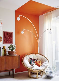 a living room with an orange accent wall and white carpeted flooring is shown