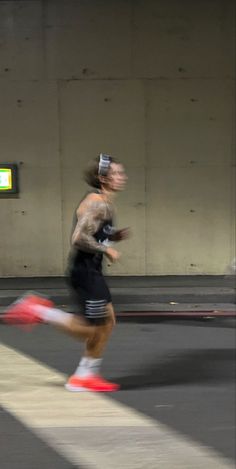 a man running in the middle of an empty parking garage with his head turned to the side