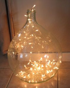 a glass bottle filled with lights sitting on top of a tile floor