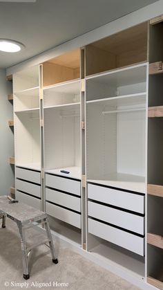 an empty walk in closet with white drawers and shelves