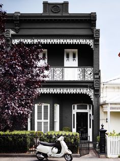 a scooter parked in front of a black and white house with balconies