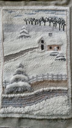 a piece of cloth with a house on it and trees in the snow behind it