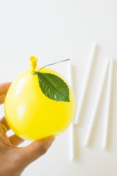 a hand holding a yellow object with green leaves on it