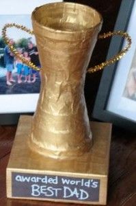 a gold trophy sitting on top of a wooden table next to two framed pictures and a plaque