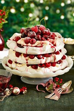 a cake with berries and whipped cream on top sitting on a table next to other desserts