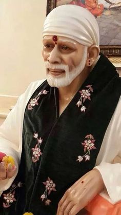 an old man with white hair and beard is holding food in his hand while wearing a turban