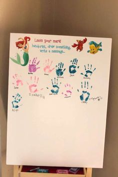 a white board with handprints on it in front of a shelf filled with children's books