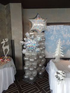 silver and white decorations are on display at a party with balloons, snowflakes, and other holiday items