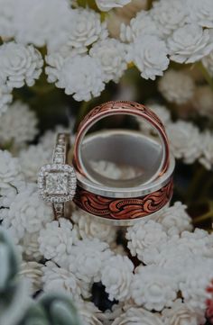 two wedding rings sitting on top of white flowers