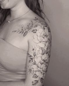 a woman with a flower tattoo on her arm and shoulder, smiling at the camera