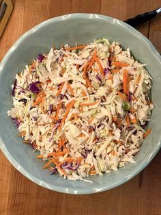 a bowl filled with coleslaw and carrots on top of a wooden table