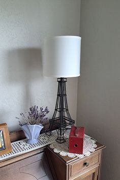 a table with a lamp and pictures on it next to a dresser in a room