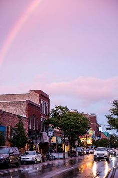 a rainbow shines in the sky over a city street