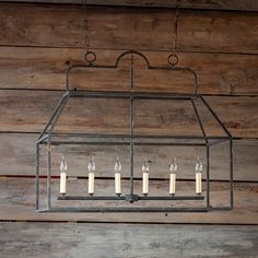 a lantern hanging from a wooden wall with candles lit in the center and on each side