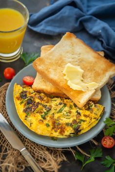 an omelet on a plate with toast, tomatoes and orange juice next to it