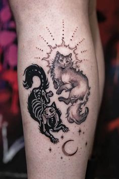 a tattoo on the leg of a woman with two cats and a moon in it