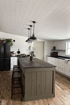 a kitchen with white cabinets and black appliances in the center, along with wooden floors