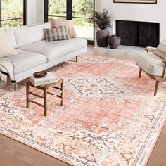 a living room filled with furniture and a large rug on top of a hard wood floor