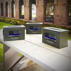 three coolers with the american flag on them are sitting on a bench in front of an old brick building