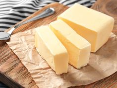 three pieces of cheese sitting on top of a wooden cutting board