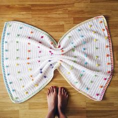 a woman's bare feet are standing next to a white bow tie on the floor