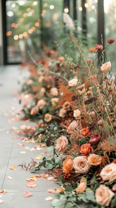 an arrangement of flowers and greenery on the ground