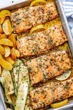 baked salmon and vegetables in a pan with lemons, zucchini, and parsley