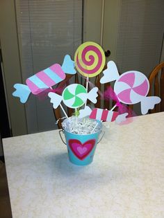 a bucket filled with candy and lollipops sitting on top of a table