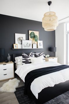 a black and white bedroom with pictures on the wall above the bed, along with an area rug