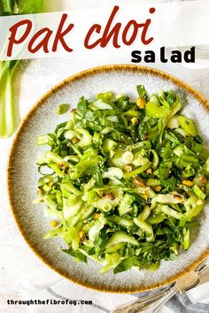 pak choi salad on a grey plate with a brown rim next to pak choy. Joi Choi Recipes, Recipes For Pak Choi, Asian Salad Vegan, Pak Choy Salad, Book Choy Salad, Vegan Pak Choi Recipes, Pal Choi Recipes, Park Choi Recipes, Recipes With Pak Choi