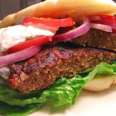 a hamburger with lettuce, tomato and onion on it sitting on a plate