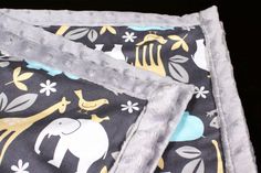 an elephant and giraffe print blanket on top of a black background with yellow, blue, and gray accents