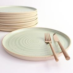 a stack of plates with forks and spoons next to each other on a white surface