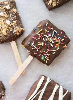 chocolate covered pops with sprinkles and marshmallows are on a table