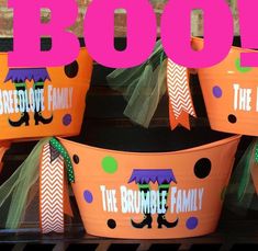 three orange buckets with the words boo on them are decorated in purple and green